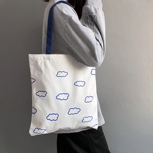 Détail latéral du sac cabas en toile avec motifs nuages bleus et anses bleu foncé