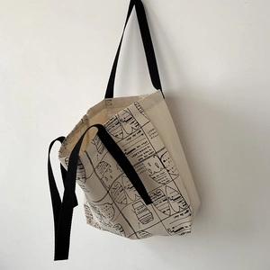 Detail of canvas tote bag with black strap and artistic comic style printed graphics