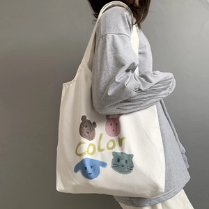 Detail of white canvas tote with cartoon animal prints and color text on model