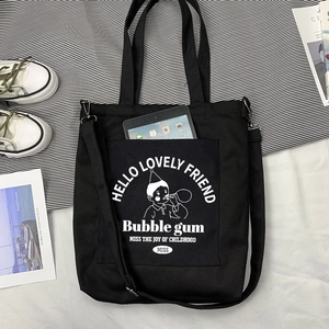Détail du sac en toile noire montrant la poche extérieure contenant une tablette