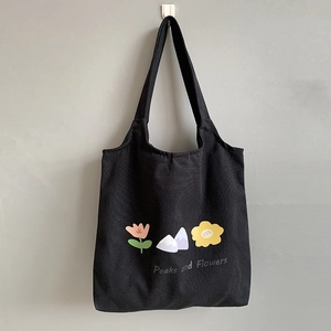Close-up of black canvas tote bag with colorful mountain and flower print details