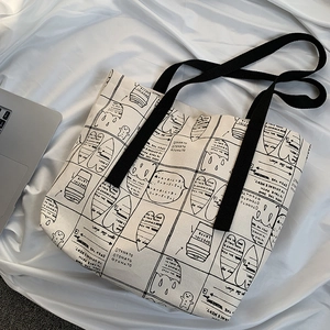 Detailed macro view of the canvas tote bag featuring black manga patterns and sturdy handles