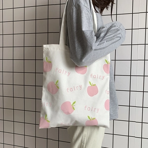 Close-up of white canvas tote bag with peach fairy print on a model's shoulder