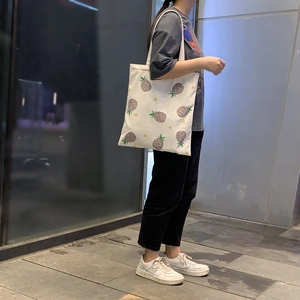 Détail d'un sac cabas en toile blanche avec imprimés ananas et fines bretelles souples