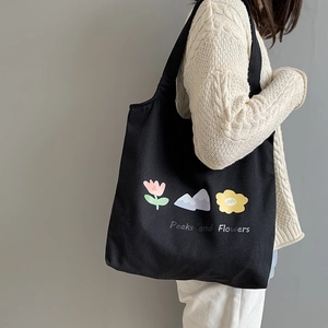 Close-up of black canvas tote with pink flower illustration and Peaks and Flowers text