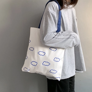 Détail du sac cabas en toile blanche avec motif nuage bleu et anses bleu foncé