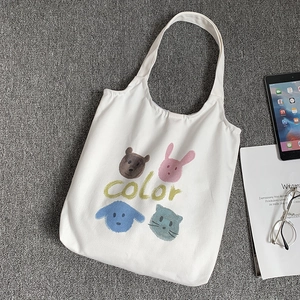 Detailed view of white canvas tote bag with pastel cartoon animal prints and color text