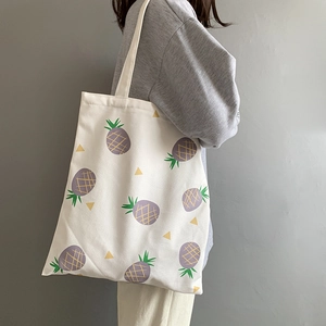 Vue détaillée du sac fourre-tout en toile blanche avec imprimé ananas violet et jaune