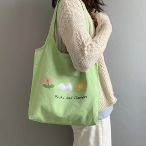 Canvas tote bag with Peaks and Flowers print worn by a model in a cozy knit sweater