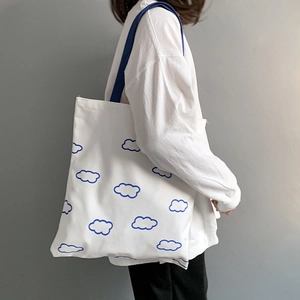 Détail d'un sac cabas en toile blanche avec imprimé nuage bleu et bretelles assorties
