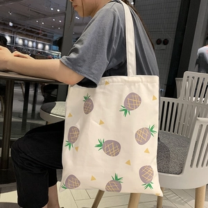 Détail du sac fourre-tout en toile blanche avec imprimé ananas violet et motifs