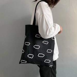 Mannequin portant un grand sac cabas noir en toile avec des motifs de nuages blancs