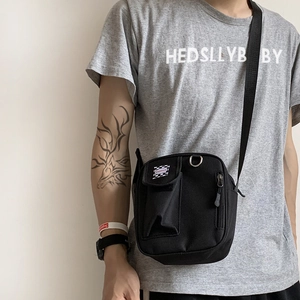 Close-up of black canvas crossbody bag with FASHION label and front velcro pocket