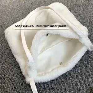 Détail du sac à main en peluche blanche avec bouton pression et doublure en tissu