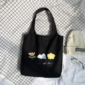 Detail of black canvas tote bag with floral print on checkered fabric background
