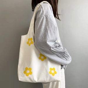Detailed texture of white canvas shoulder bag featuring vibrant yellow flower prints