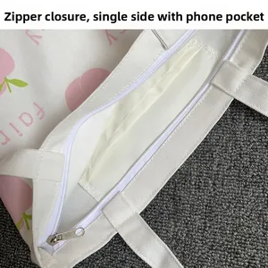 Detail view of the zipper closure and internal phone pocket of a peach canvas tote bag