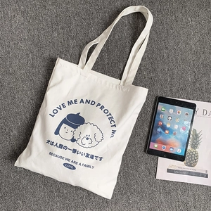 Gros plan détaillé d'un sac cabas en toile blanche avec illustrations bleues de fille et chien