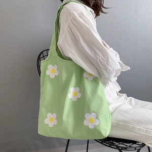 Detail of light green canvas tote bag featuring fresh white daisy pattern and sturdy straps