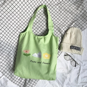 Detail of light green floral canvas tote bag with Peaks and Flowers print on checkered cloth
