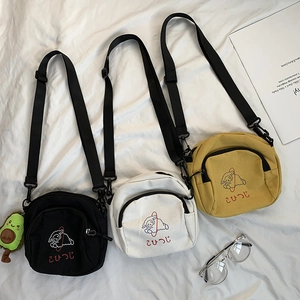 Détail à plat de petits sacs bandoulière en toile avec broderie mouton et charme avocat