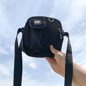 Black canvas crossbody bag with checkered pattern and fashion print against a blue sky