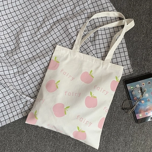 Detailed view of white canvas tote bag with pink peach print and fairy text