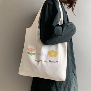 Detail of a white canvas tote bag with floral print and Peaks and Flowers text