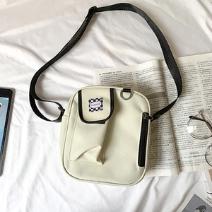 Detail of a beige canvas crossbody bag with Fashion label on a white fabric background