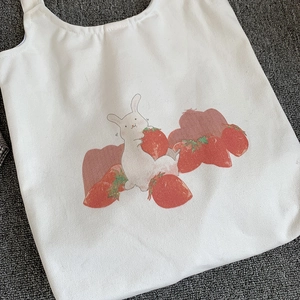 Détail du sac en toile blanche avec motif mignon de lapin et fraise dessiné à la main