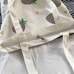 Détail de la fermeture éclair en métal argenté sur un sac fourre-tout en toile crème