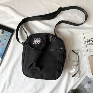 Detail of black canvas messenger bag featuring fashion label and adjustable shoulder strap