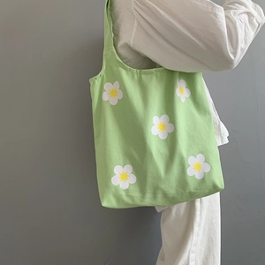 Detail of light green floral canvas tote bag featuring daisy patterns on shoulder strap
