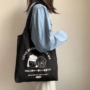 Détail du sac cabas noir en toile avec illustration porté à l'épaule pour femme
