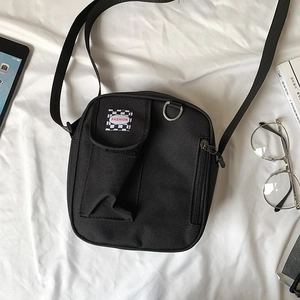 Close-up of black nylon crossbody bag with fashion label and zipper detail on fabric