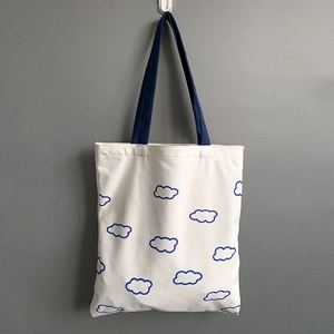 Détail du sac cabas en toile avec motifs de nuages bleus et anses bleu foncé