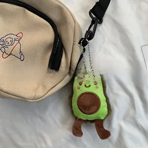 Détail du sac bandoulière en toile beige avec motif mouton et breloque avocat en peluche