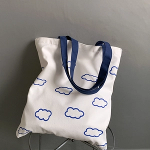 Détail du sac en toile blanc avec motif nuages bleus et anses bleu foncé