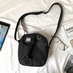 Detail of black canvas crossbody bag with checkerboard patch and adjustable shoulder strap
