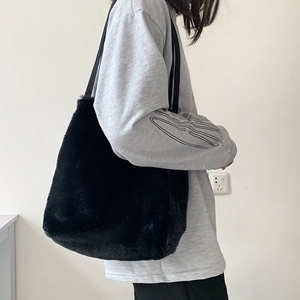 Vue latérale d'un sac cabas noir en fausse fourrure duveteuse avec des bandoulières tissées