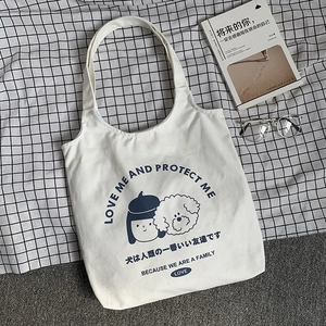 Gros plan sur un sac cabas en toile blanc cassé avec motif fille et chien bleu marine