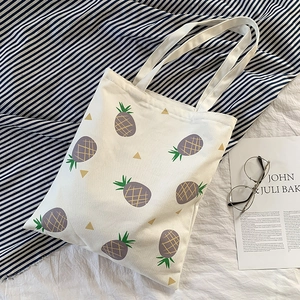 Détail du sac cabas en toile blanche avec imprimé ananas violet et motifs de feuilles