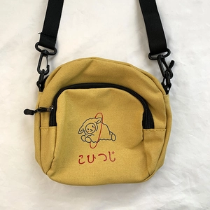 Détail du sac bandoulière en toile jaune avec un agneau bleu et texte japonais