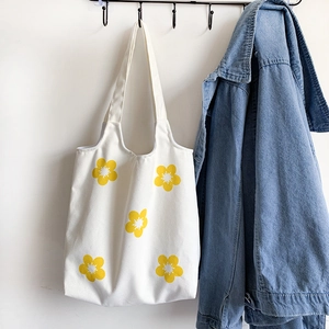 Detail of white canvas tote bag featuring five hand-painted yellow flowers on hooks