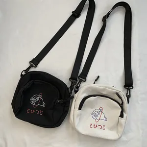 Détail de la broderie mouton sur des sacs en toile noir et blanc avec bandoulières en nylon