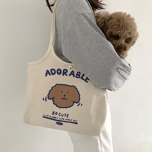 Detail einer beigen Canvas-Tragetasche mit Teddyhund-Aufdruck und Metalldruckknopf