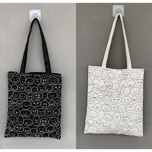 Detail of canvas tote bags with smile patterns and cute lamb plush pendant charm