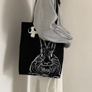 Detail view of large black canvas shoulder bag with cute rabbit print and panda pendant