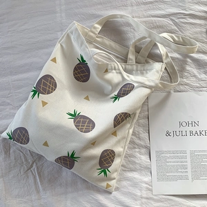 Détail du motif d'ananas et de la fermeture éclair sur le sac cabas en toile blanc cassé