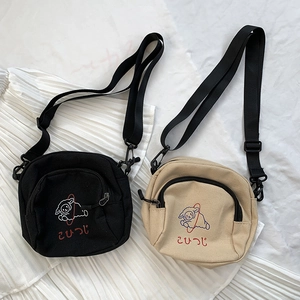 Détail de sacs bandoulière en toile noir et beige avec broderie mouton mignonne